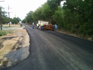 Construction equipment, crew, and trucks on road